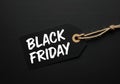 A black price tag tied with string on a dark background, with Black Friday written in brush script Royalty Free Stock Photo